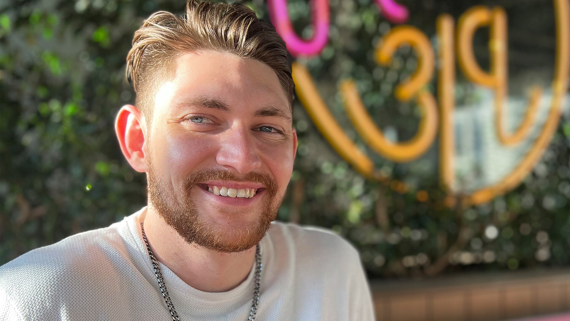 Athlete Harley Windsor smiles to the camera, wearing a white t-shirt and silver chain necklace.