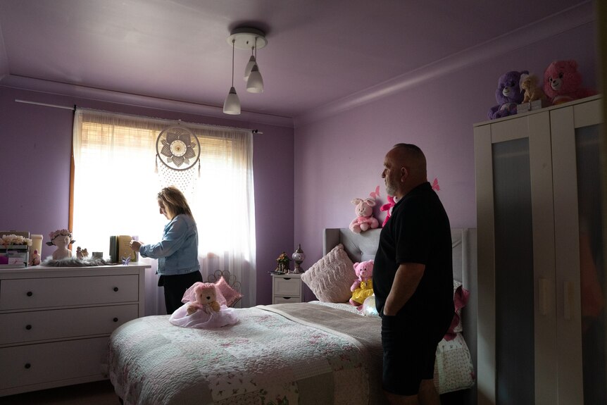 A woman and a man look at items in a girl's bedroom.