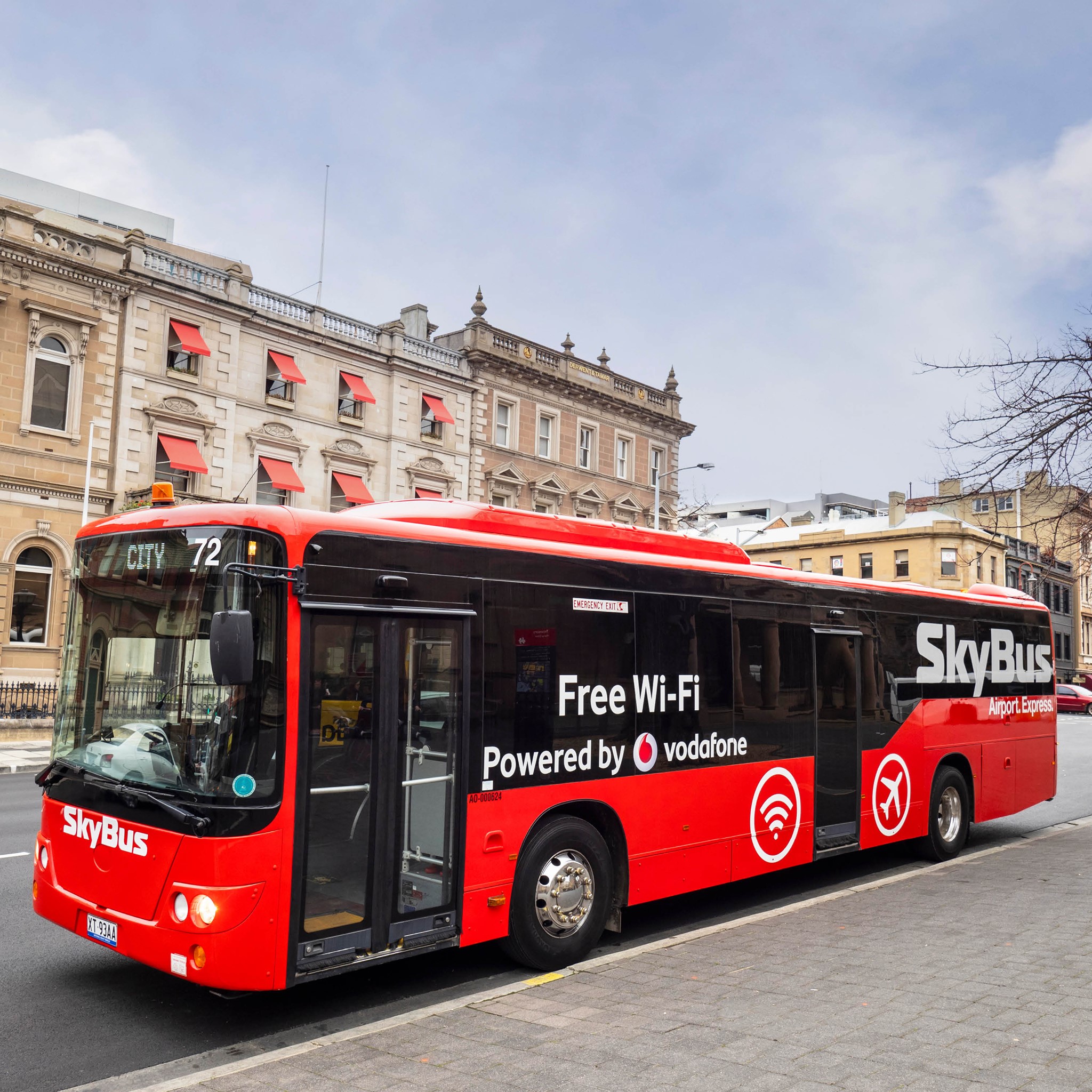 Um grande ônibus vermelho em frente a edifícios históricos de tijolos.
