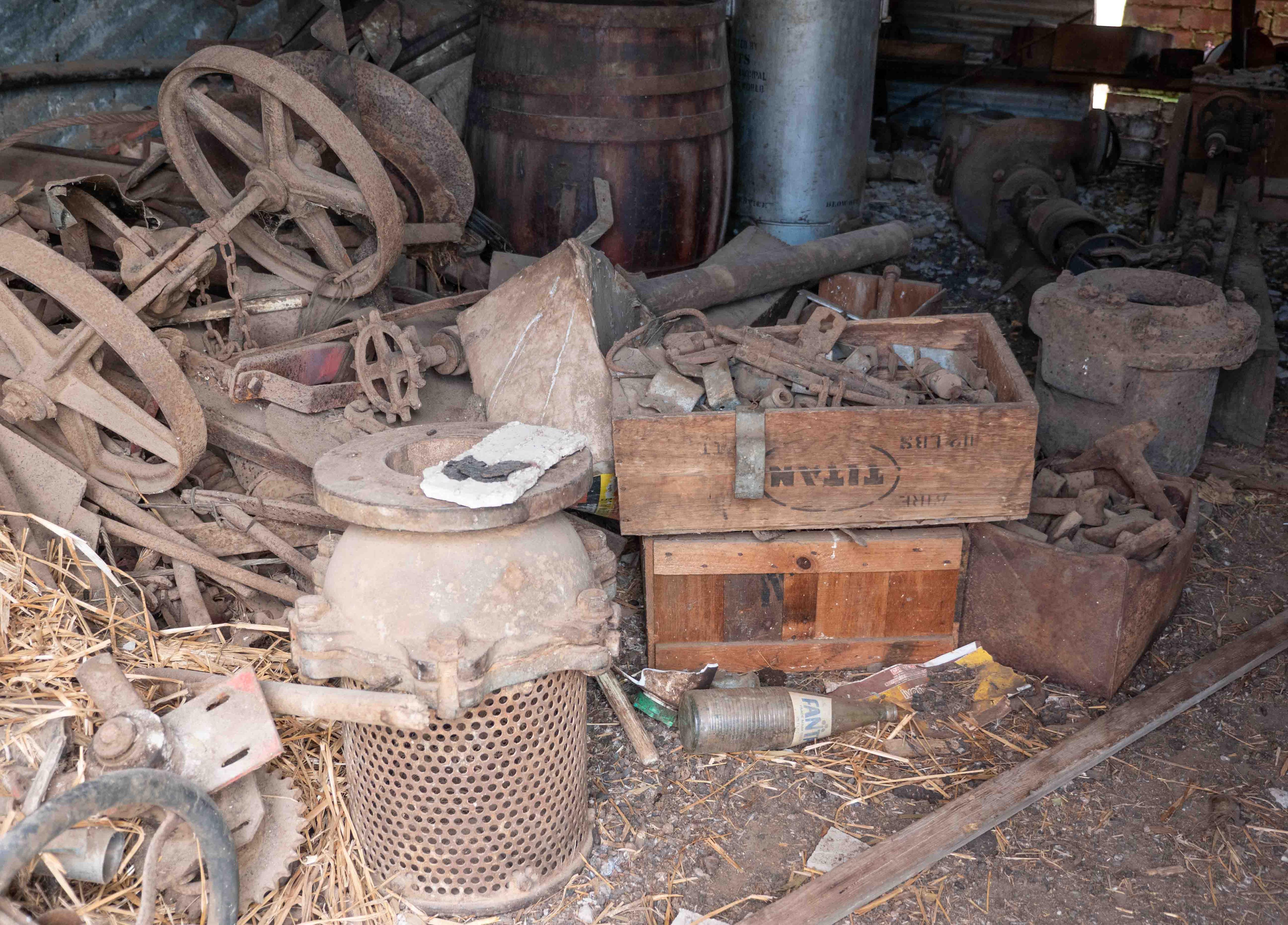 Old rusty farm items including a box of bolts and cart wheels