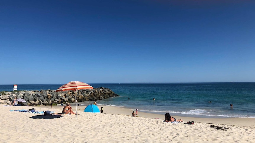 People sit on Floreat Beach, enjoying the weather.