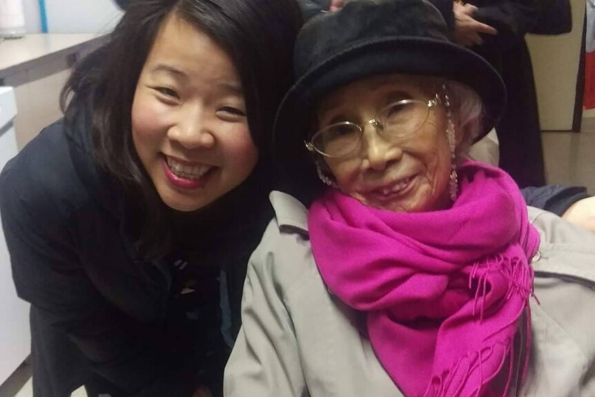 Close-up photo of Beverley Wang smiling widely with head held close to elderly woman smiling.