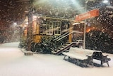 snow blowing at a train station at night