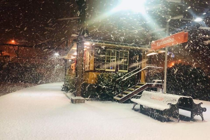 snow blowing at a train station at night