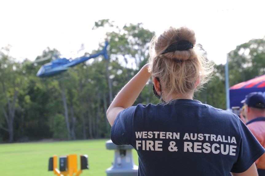 An emergency services worker watches on as helicopter takes off