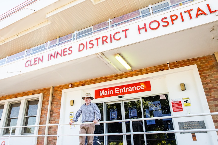 Man stands in front of hospital.