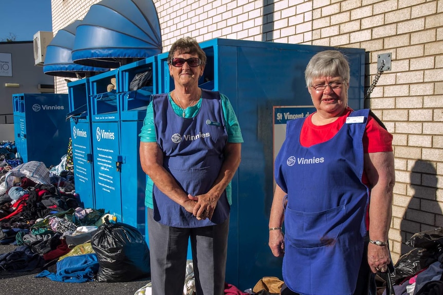 Two st vincent de paul volunteers near clothing bins with clothing strewn on the ground