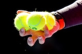 A close-up of a player's hand rotating three Australian Open-branded tennis balls between his fingers