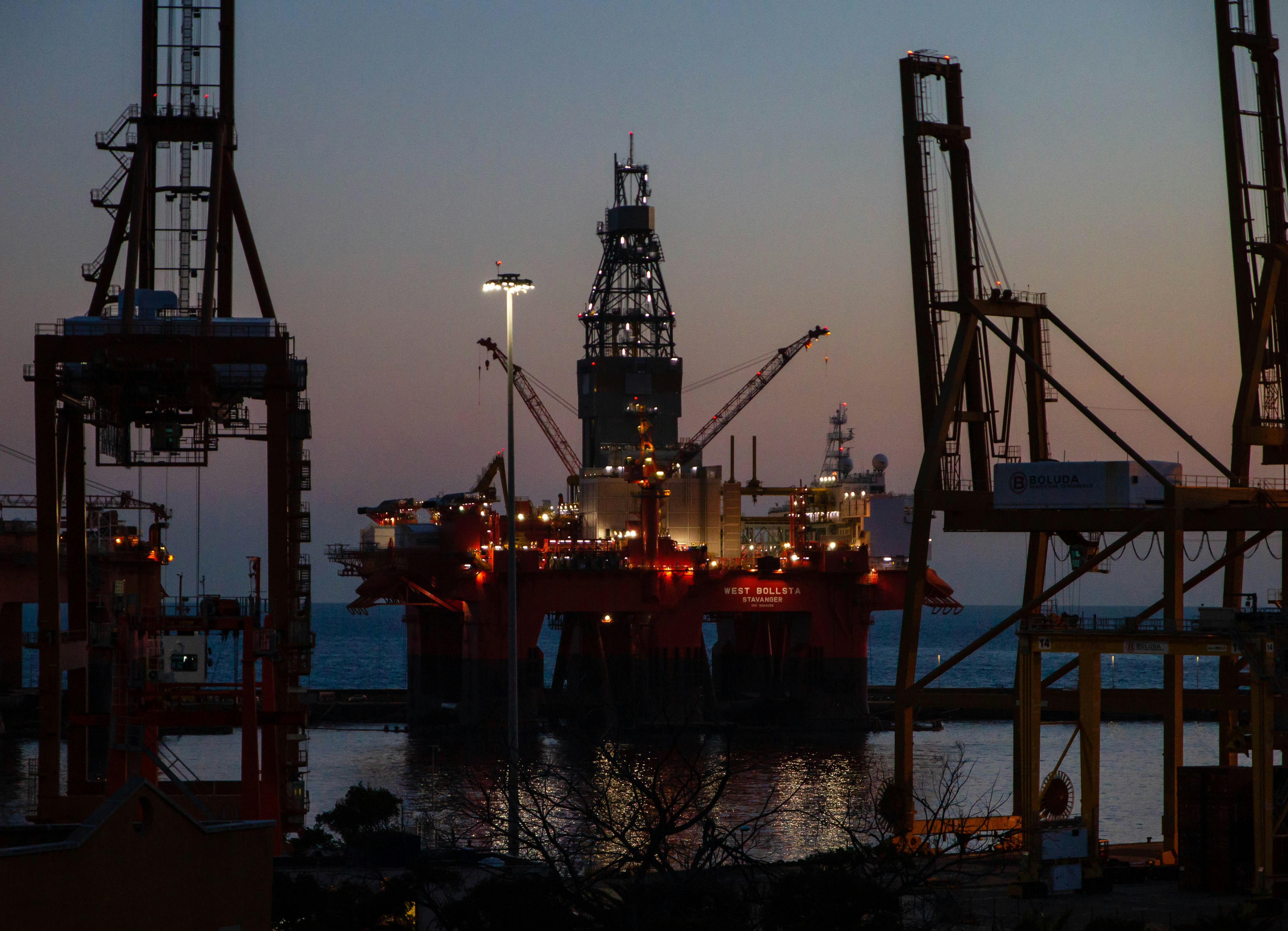 Brightly lit towers of an oil drilling rig in the ocean.