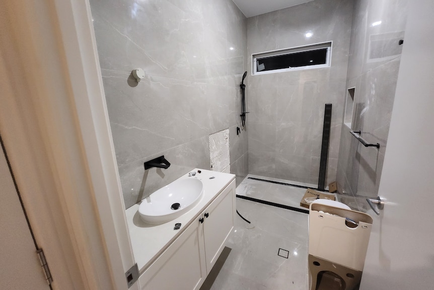 an unfinished bathroom in a partially built house with grey tiles and black fixtures