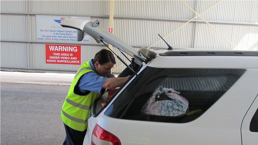 An inspector looks into the boot of a car