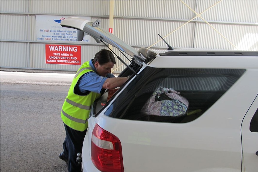 An inspector looks into the boot of a car