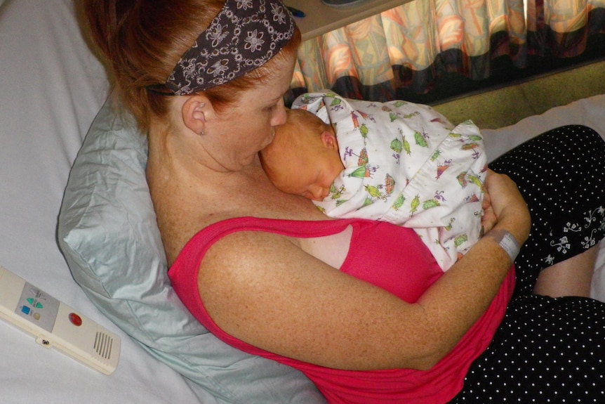 A woman holds her newborn baby.