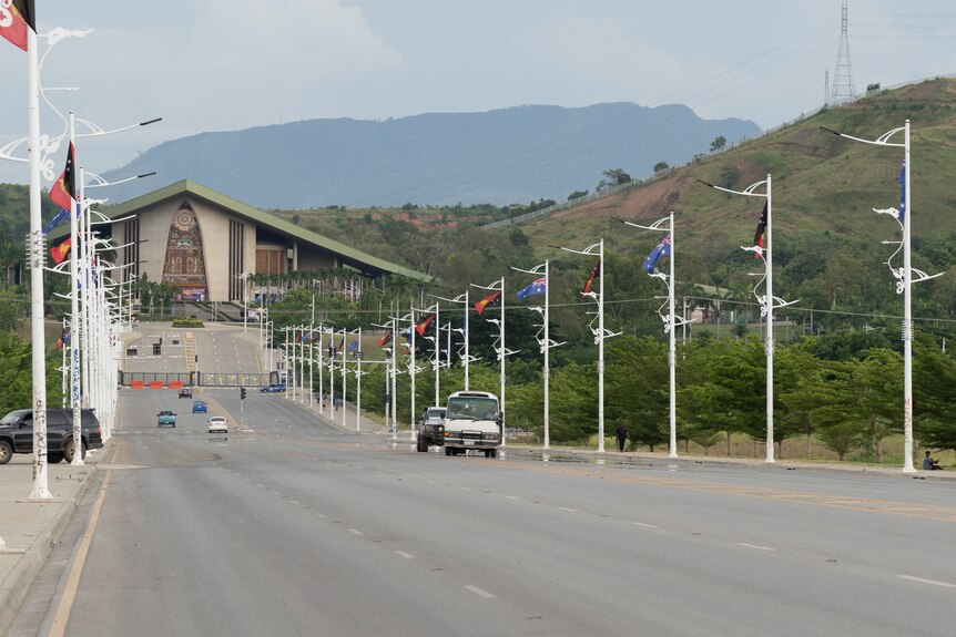 A view of street leading up to PNG parliament lined with PNG and Australian flags