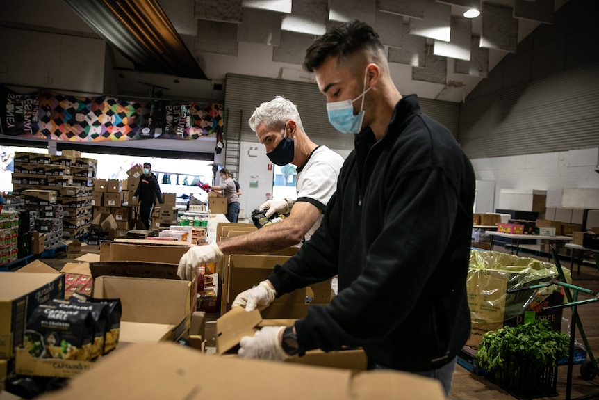 people wearing masks filling food parcels