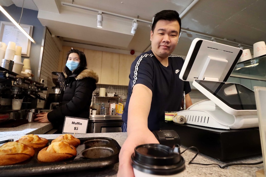 Cafe workers Ticha Naksomyat, wearing a face mask, and Hery Liu at work in inner-Sydney.