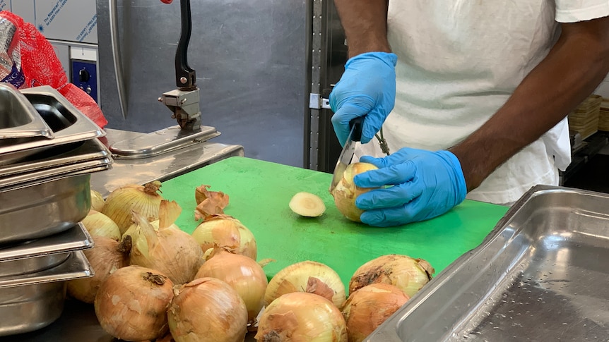 Prisoner chopping onions for food preparation in West Kimberley Regional Prison kitchen.