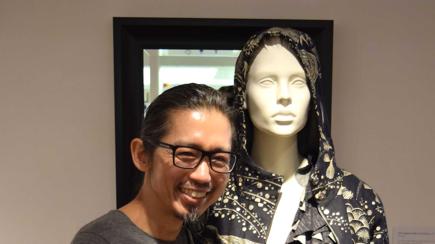 A man stands next to a mannequin wearing a monochrome outfit