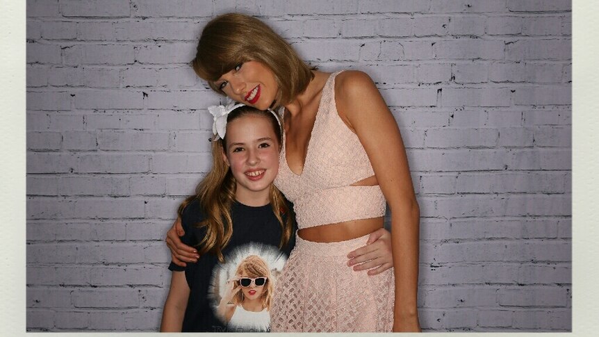 Young girl standing side by side and hugging pop star Taylor Swift.