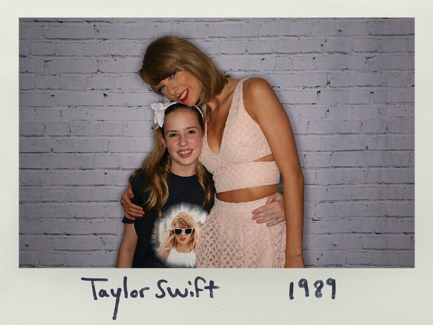 Young girl standing side by side and hugging pop star Taylor Swift.