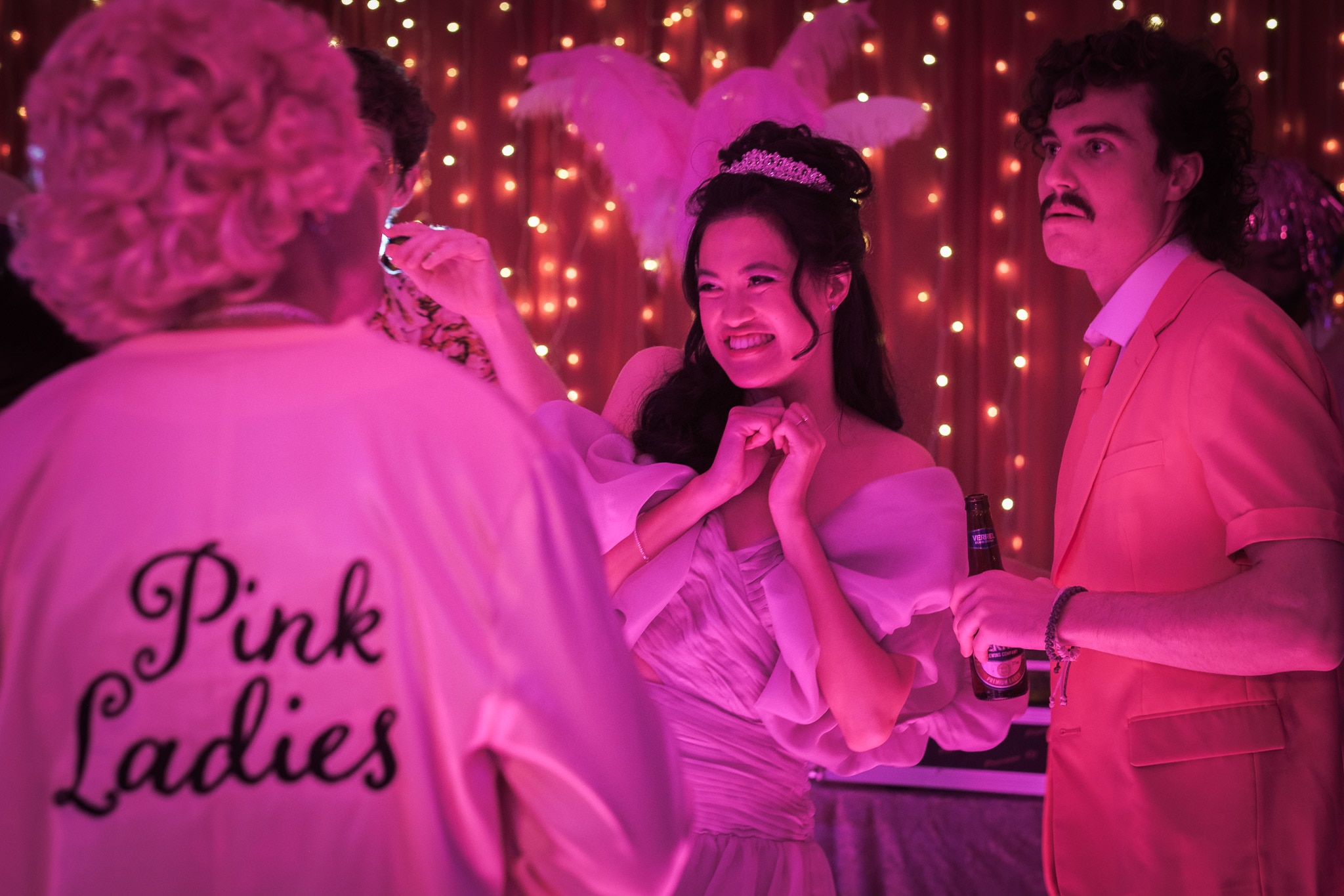 Tiffany wears a pouffy dress and tiara and holds her hands together in glee as she smiles at someone off-camera.