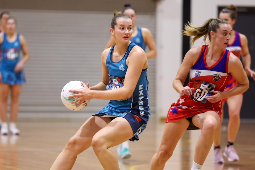 A girl holding a netball, about to make a pass.
