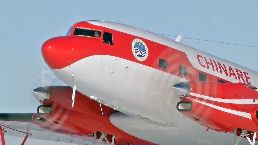 A red and white plane with the pilot visible