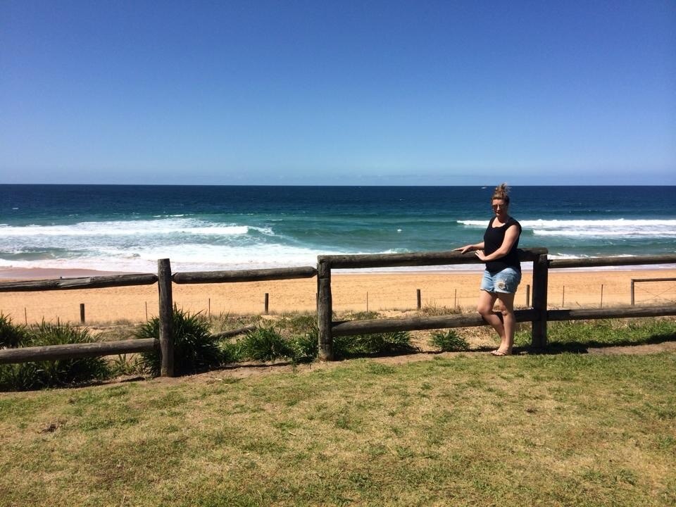 Aleisha Hausler leans up against a railing at a beach in Warrnamool