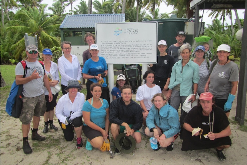 A large group of people who volunteered to clean up debris on the beaches pose for a group photo on the tropical island.