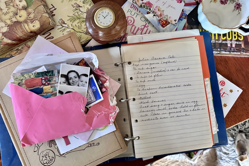 Top-down image of paper clutter including photos, birthday cards, thank you notes, a handwritten banana cake recipe.