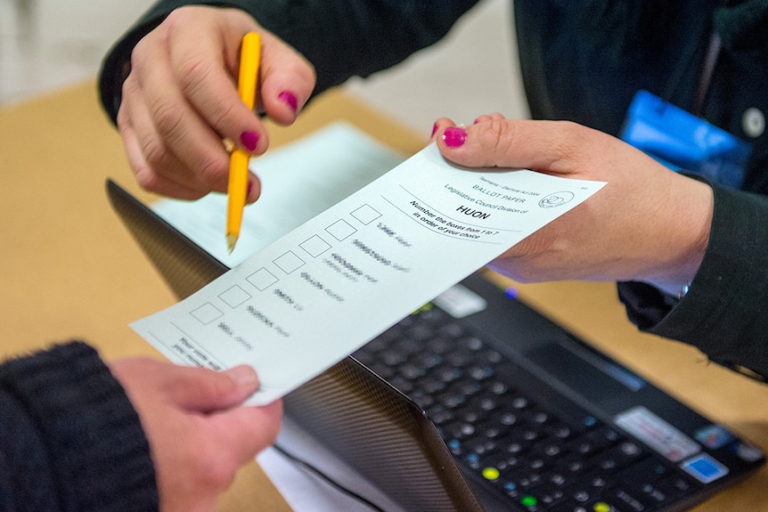 Electoral official pointing to ballot paper.