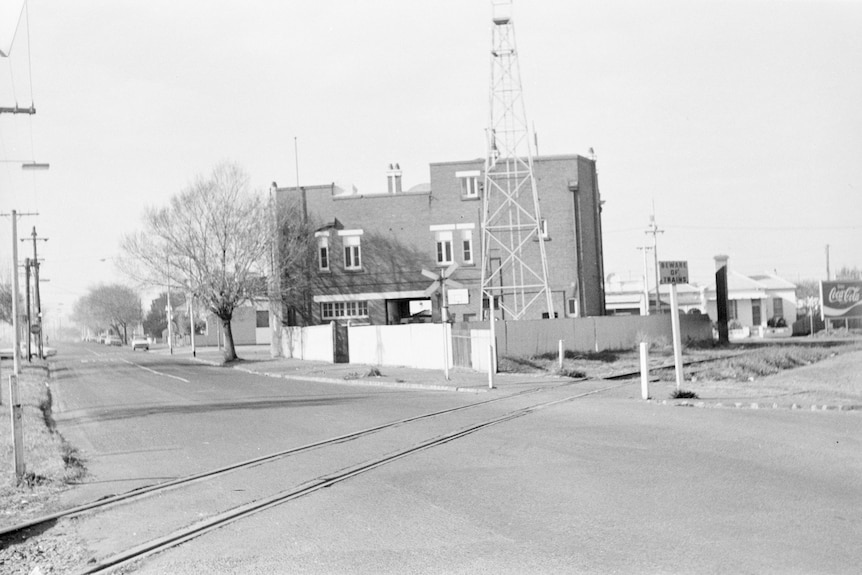 A black and white photo of a railway crossing.