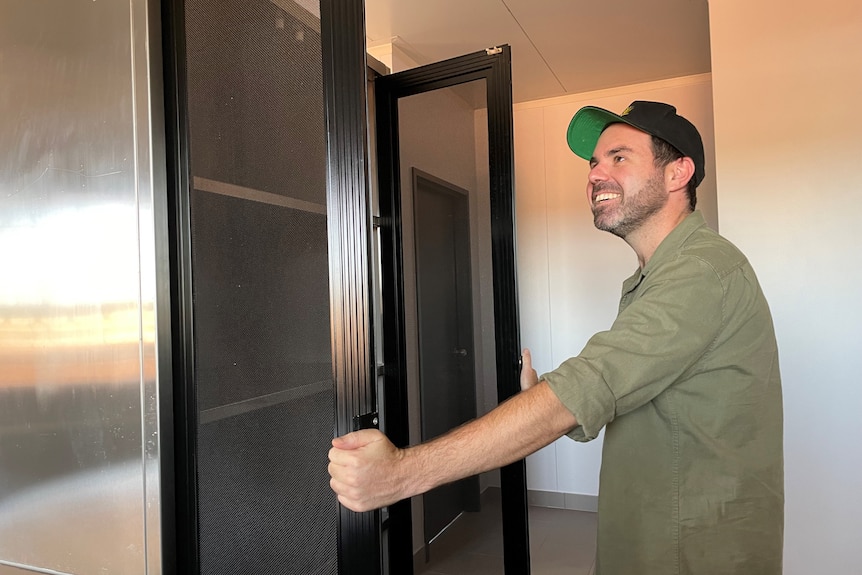 a man wearing a cap opens a stainless steel pantry