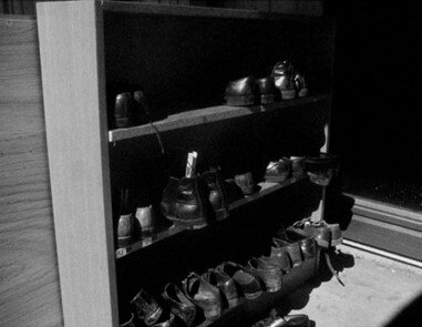 Black and white image of shoes on a shelf.