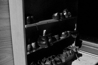 Black and white image of shoes on a shelf.