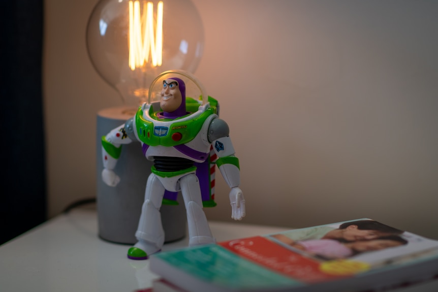 A Buzz Lightyear statue beside a book with Korean people on the cover