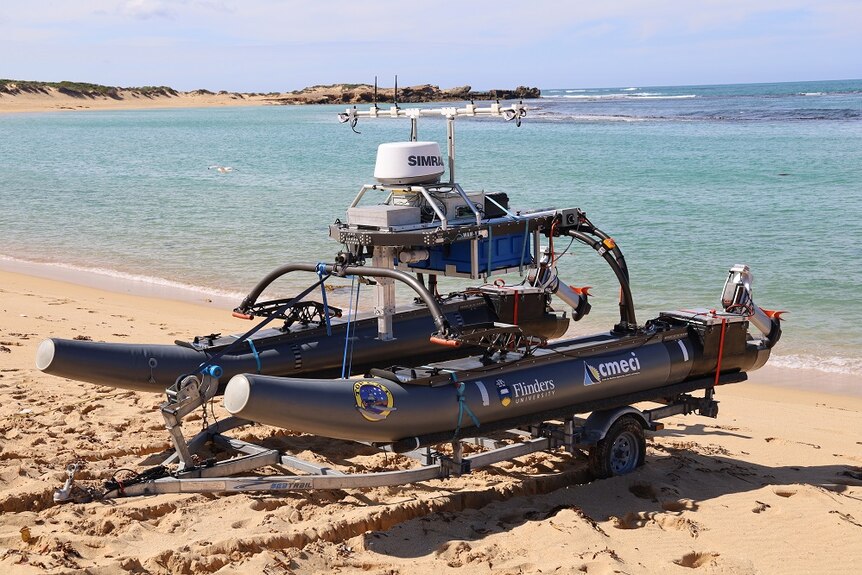 A boat with navigation technology sits on a trailer on sand