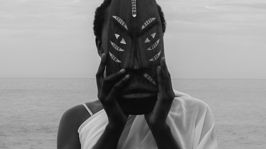 woman holds Solomon Island mask to cover face
