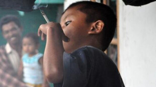 An Indonesian child holding a cigarette.