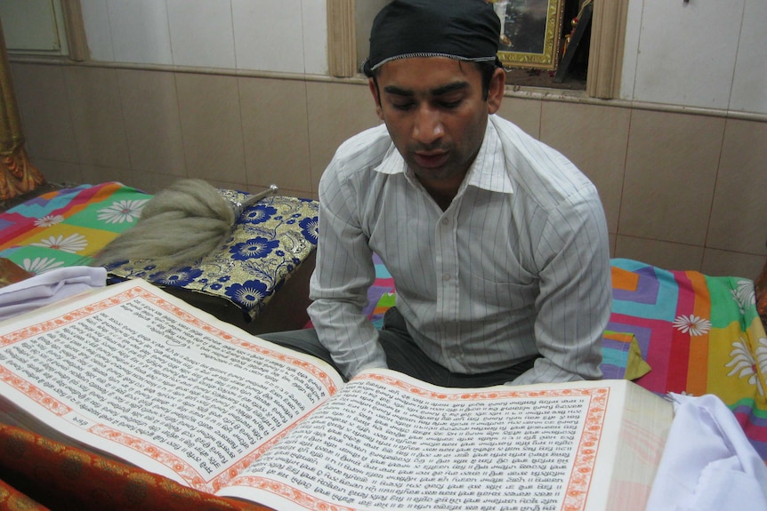 A young Hindu recites from a holy book in a local temple.