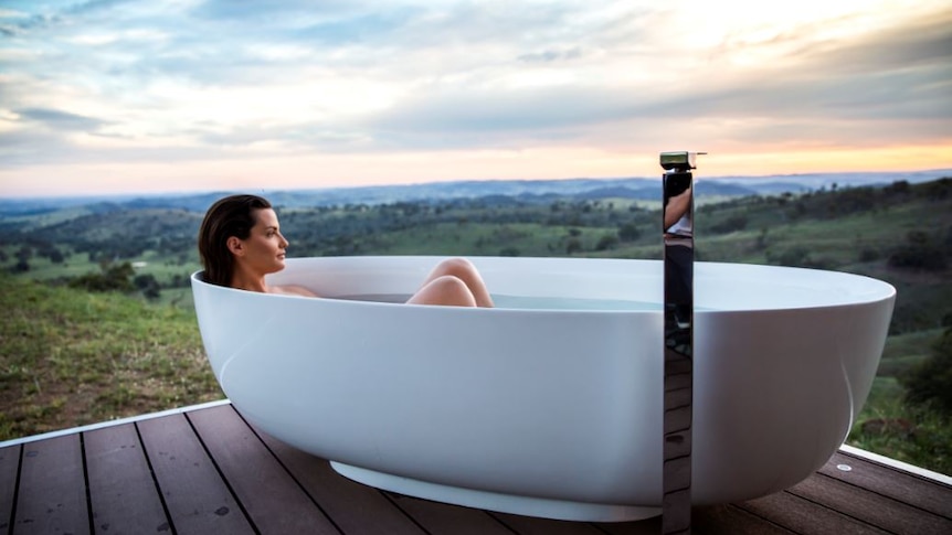 A woman sits in a bathtub with a beautiful view