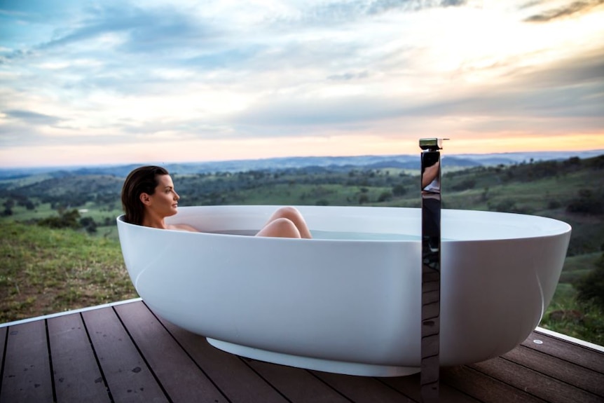 A woman sits in a bathtub with a beautiful view