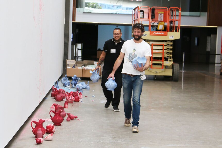 Artist Ben Quilty walks through GOMA art gallery with pots used for painting on 4 June, 2019.