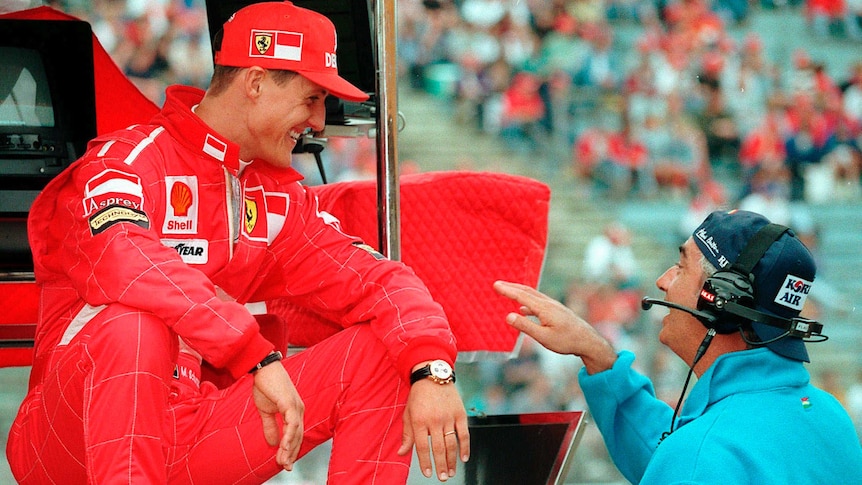 Ferrari's Michael Schumacher (L), jokes with Benetton chief Flavio Briatore at Hockenheim in 1997.