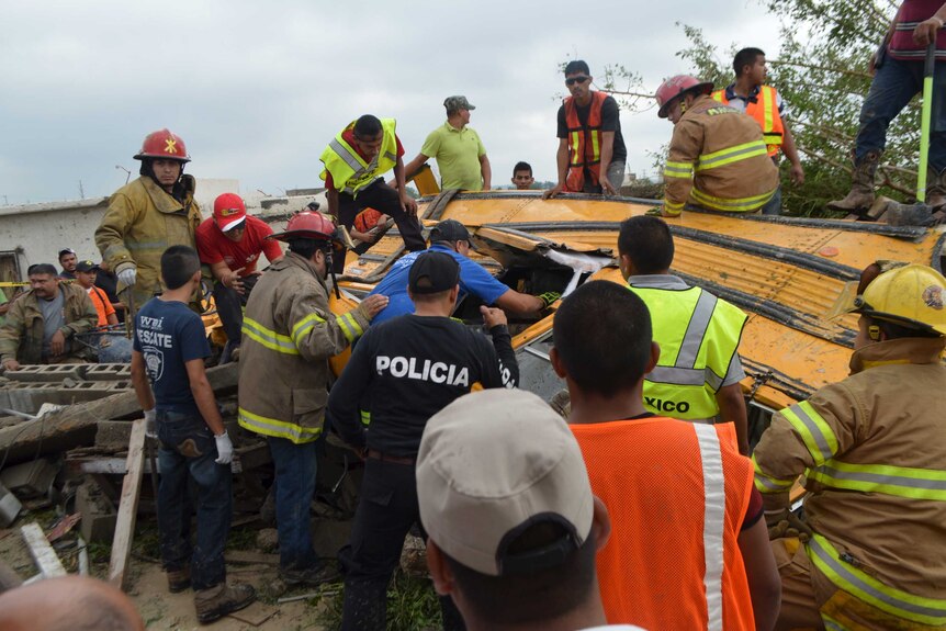 Firefighters inspect a tornado damaged bus
