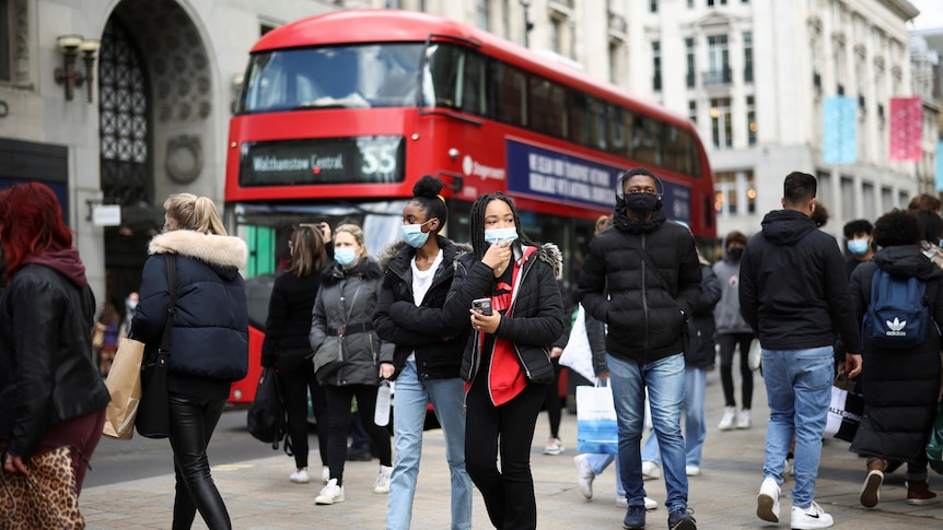 People walking along Oxford Street with a red double decker bus in the background.