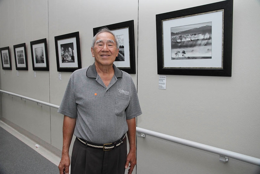 A man standing in front of his photographic exhibition