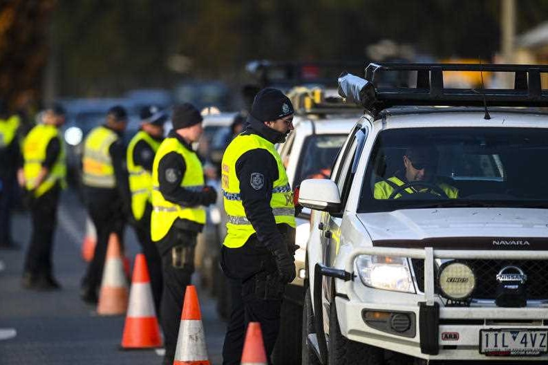 A line-up of people checking cars on a road.