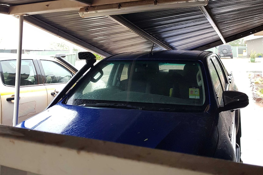 A carport that has collapsed onto a car.