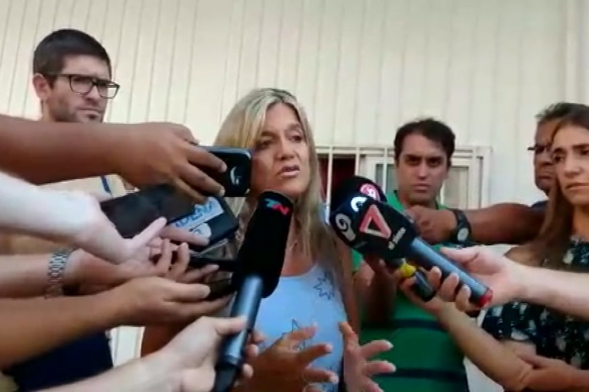 A female police prosecutor talking in front of several media microphones.